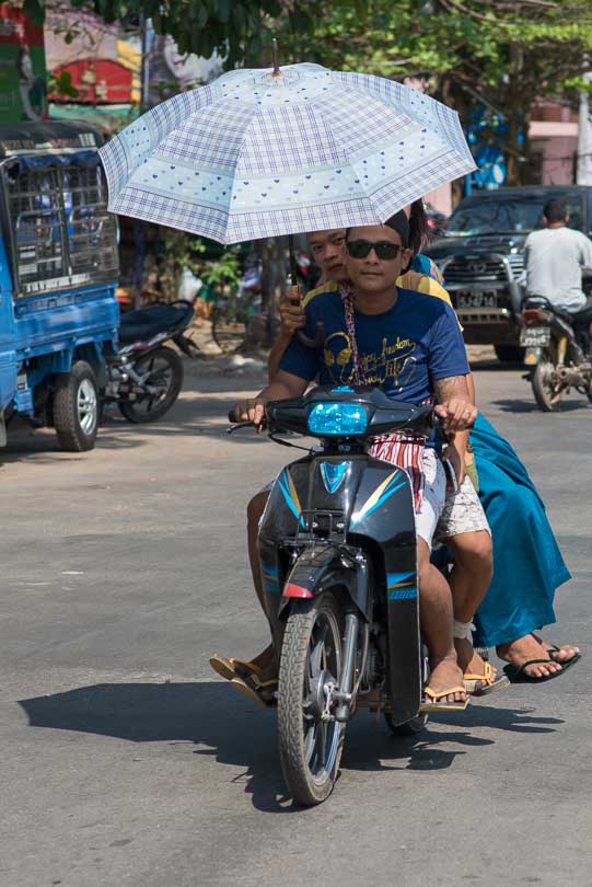 Menschen auf einem Mopedmit Sonnenschirm in Myanmar